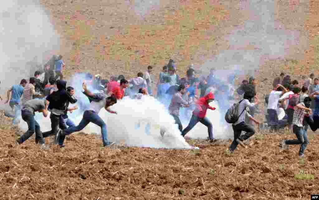 Para demonstran berlarian saat gas air mata meledak di lapangan selama aksi protes di dekat Universitas Dicle, di kota Diyarbakir, Turki.