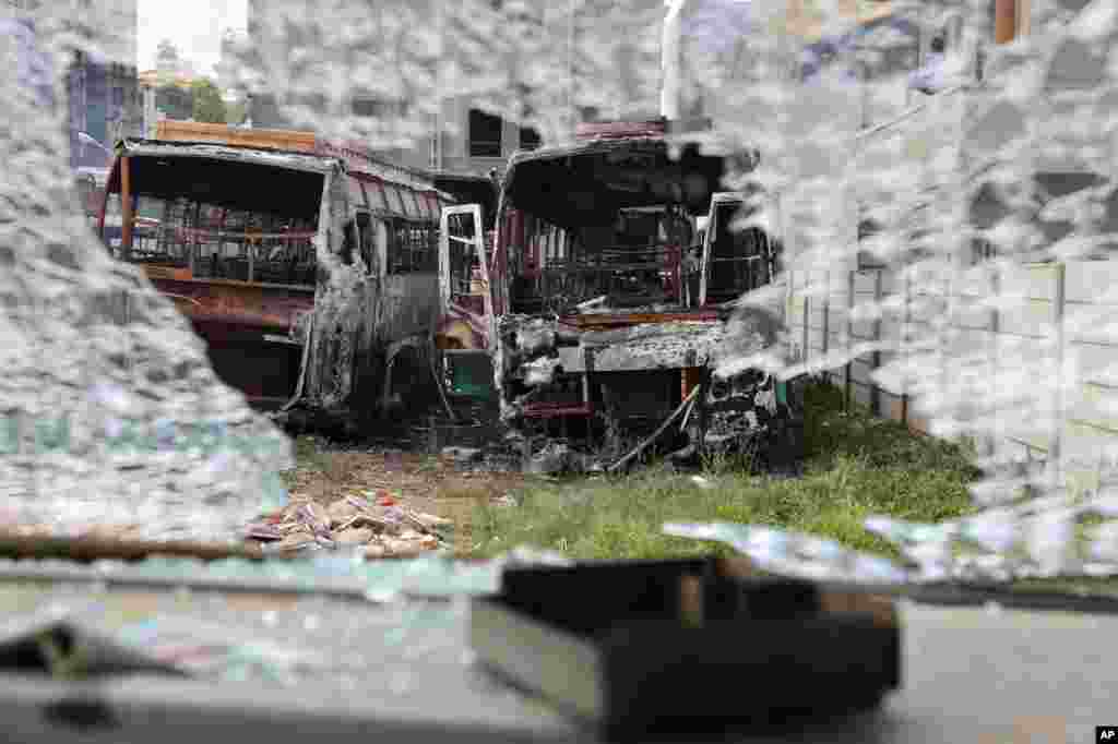 Charred remains of passenger buses owned by a transport company from the neighboring Tamil Nadu state, are seen through the shattered glass of another bus vandalized by angry mobs in Bangalore, capital of the southern Indian state of Karnataka. Authorities imposed a curfew amid widespread protests overnight over the country's top court ordering the southern state of Karnataka to release water from a disputed river to the neighboring state.