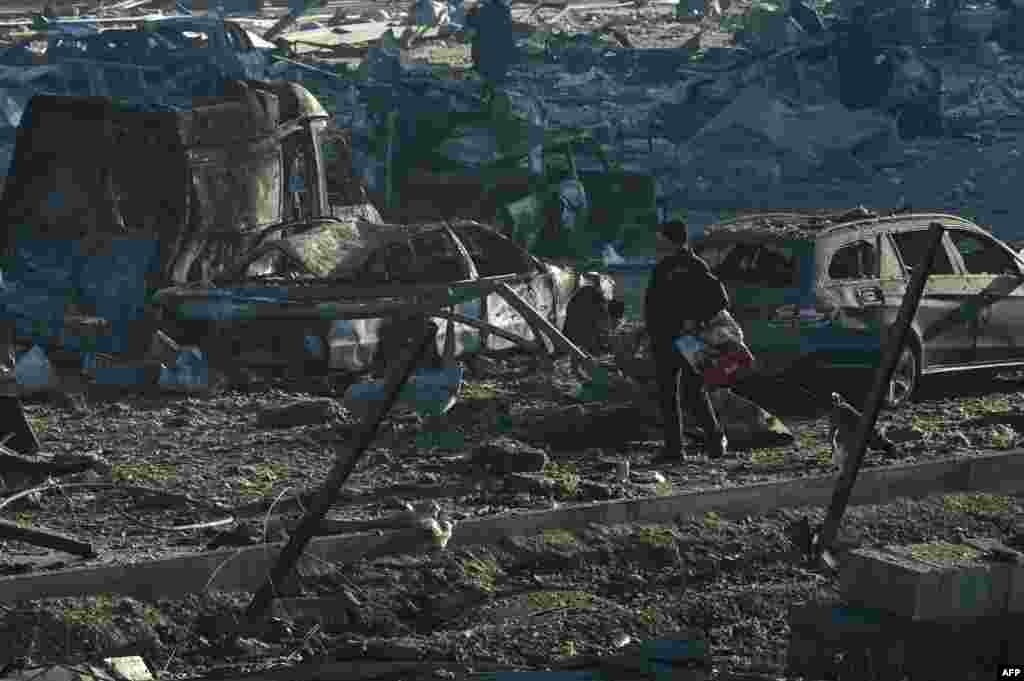 A man walks his dog past burnt out vehicles and debris following a Russian missile attack on the Retroville shopping mall in Kyiv, Ukraine, March 21, 2022.