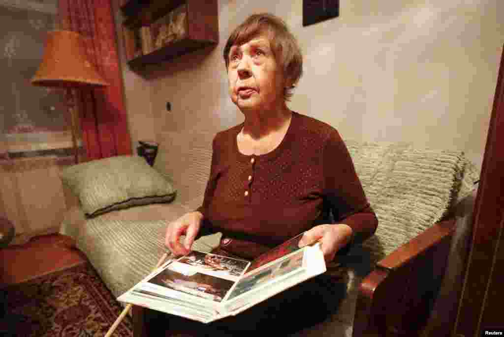 Varvara Tolokonnikova, nenek Nadezhda Tolokonnikova, memperlihatkan foto-foto keluarga dari Nadezhda di apartemennya, sambil menunggu cucunya dibebaskan dari penjara (21/12). (Reuters/Ilya Naymushin)