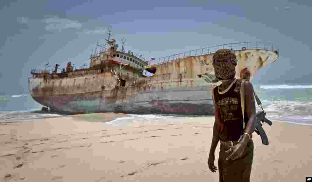 Seorang bajak laut dengan wajah tertutup kain berdiri dekat kapal nelayan Taiwan yang tersapu ke pantai di Hobyo, Somalia (23/9/2012) setelah para pembajak mendapat uang tebusan dan melepaskan para awak kapal. (AP/Farah Abdi Warsameh)