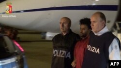 Foto yang dirilis oleh kepolisian Italia ini menunjukkan gambar Yehdego Mered (35 tahun, berkaos merah), warga Eritera yang diduga mendalangi jaringan penyelundup migran ke Italia diekstradisi dari Sudan ke Italia (8/6). 