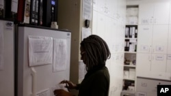 FILE - In a Nov. 30, 2016 file photo, pharmacist Mary Chindanyika looks at documents on a fridge containing a trial vaccine against HIV on the outskirts of Cape Town, South Africa.