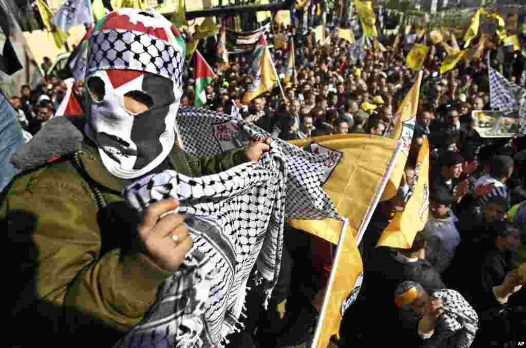 A masked Palestinian holds a traditional Arab headdress during Fatah anniversary celebration in the West Bank city of Nablus, January 3, 2013.