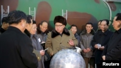 김정은 북한 국무위원장이 핵무기 연구 부문 과학자, 기술자들을 만나 핵무기 병기화 사업을 지도했다며 지난 2016년 3월 관영 조선중앙통신이 공개한 사진. 아래쪽에 핵탄두 기폭장치 추정 물체가 보인다.