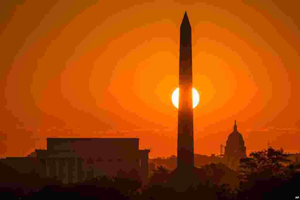 Matahari pagi tepat berada di balik Washington Monument di kota Washington DC.
