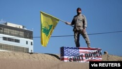 Участник похорон Касема Сулеймани держит в руках флаг "Хезболлы". Керман, Иран. 7 января 2020 года
