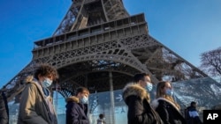 Orang-orang yang berjalan melewati Menara Eifel di Paris, Prancis, tampak mengenakan masker untuk mencegah perebakan COVID-19, pada 21 Desember 2021. Eropa telah mencatat lonjakan kasus baru COVID-19 sejak varian Omicron terdeteksi. (Foto: AP/Michel Euler)