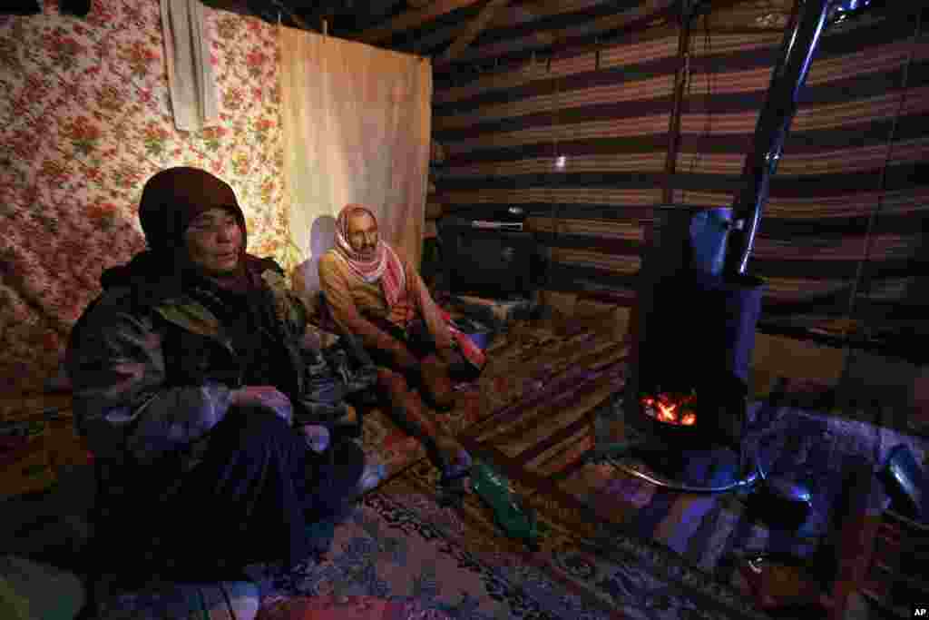 Pengungsi Suriah Ahmed al-Hasan dan istrinya Mariam al-Hamed duduk di dalam tenda mereka di kamp pengungsi dekat kota Romawi kuno Baalbek di Lebanon timur (15/12). (AP/Bilal Hussein)