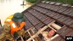 Một phụ nữ rơi nước mắt chờ được cứu ra khỏi ngôi nhà bị ngập ở tỉnh Hà Tĩnh, Việt Nam, ngày 17/10/2010