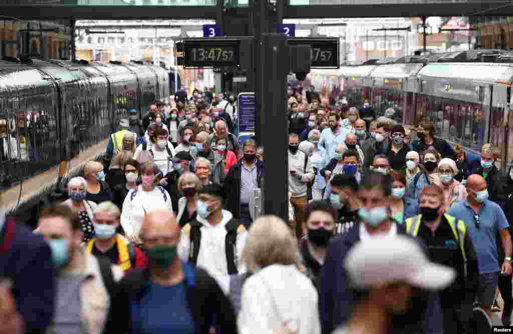People wearing protective face masks walk along a platform at King's Cross Station in London.