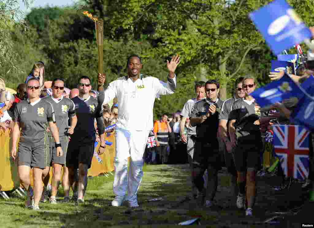 Former world heavyweight boxing champion Lennox Lewis carries the Olympic torch through Danson park in Bexley, south east London as part of the torch relay ahead of the London 2012 Olympic Games July 22, 2012.