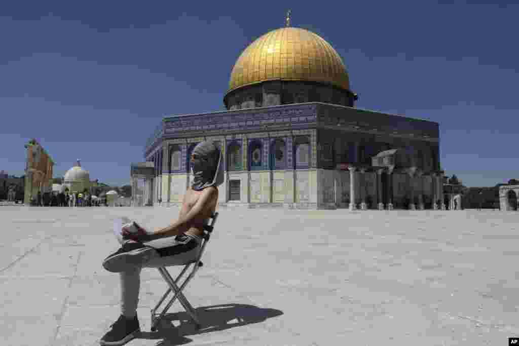 A masked Palestinian demonstrator holds a stone during clashes with Israeli security forces in front of the Dome of the Rock Mosque at the Al Aqsa Mosque compound in Jerusalem's Old City.