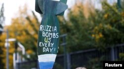 Плакат на митинге в Брюсселе против российских бомбардировок Украины.