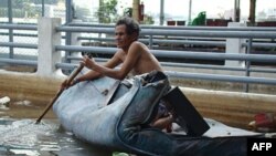 Một người dân ngồi trên một tấm nệm chèo dọc theo sông Chao Pghraya, con sông chảy ngang qua thủ đô Bangkok của Thái Lan