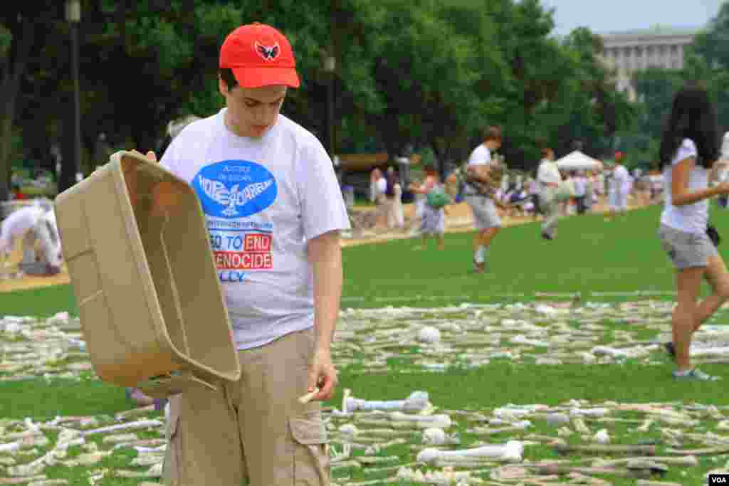 Tenaga sukarela menaruh tulang-tulang simbolis pada instalasi "One Million Bones" (Sejuta Tulang) di taman National Mall, Washington DC (8/6). (VOA/Jill Craig)
