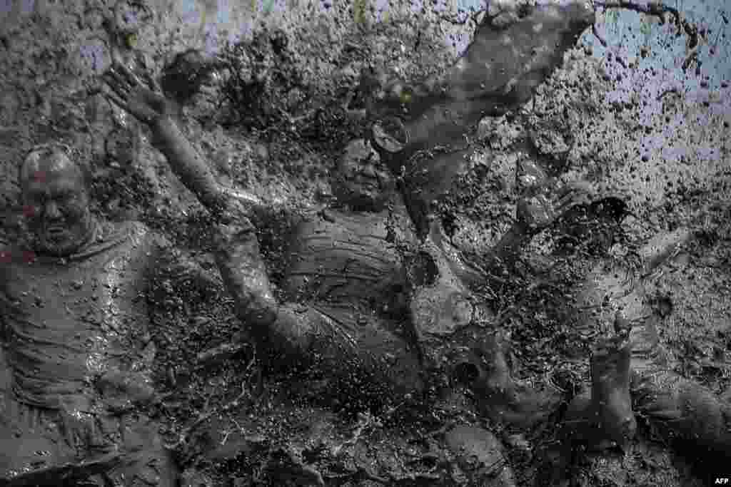 Mud-covered farmers play in a rice paddy field during "National Paddy Day", which marks the start of the annual rice planting season, in Tokha village on the outskirts of Kathmandu, Nepal, June 29, 2021.